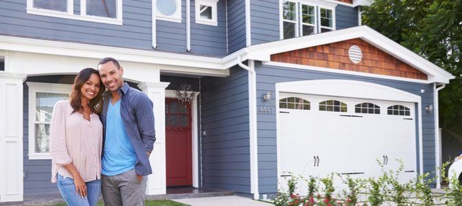 A couple standing in front of their new home