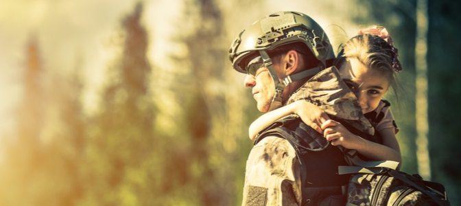 A father in a military uniform being hugged by his daughter.