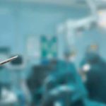 An anesthesiologist with a clipboard in an operating room